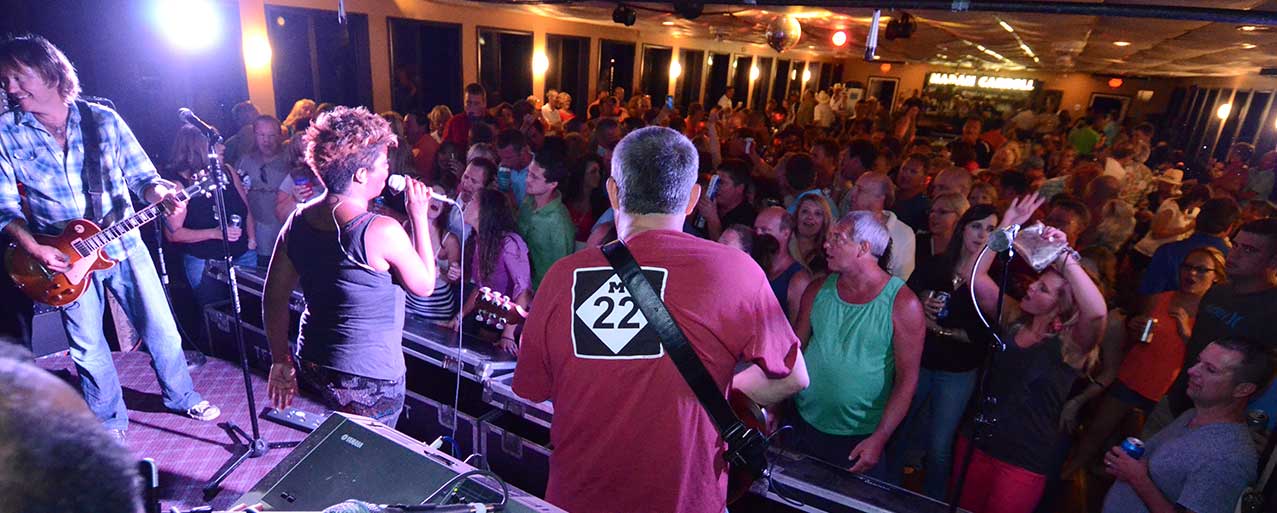 A packed dance floor with a live band and disco ball on an entertainment cruise
